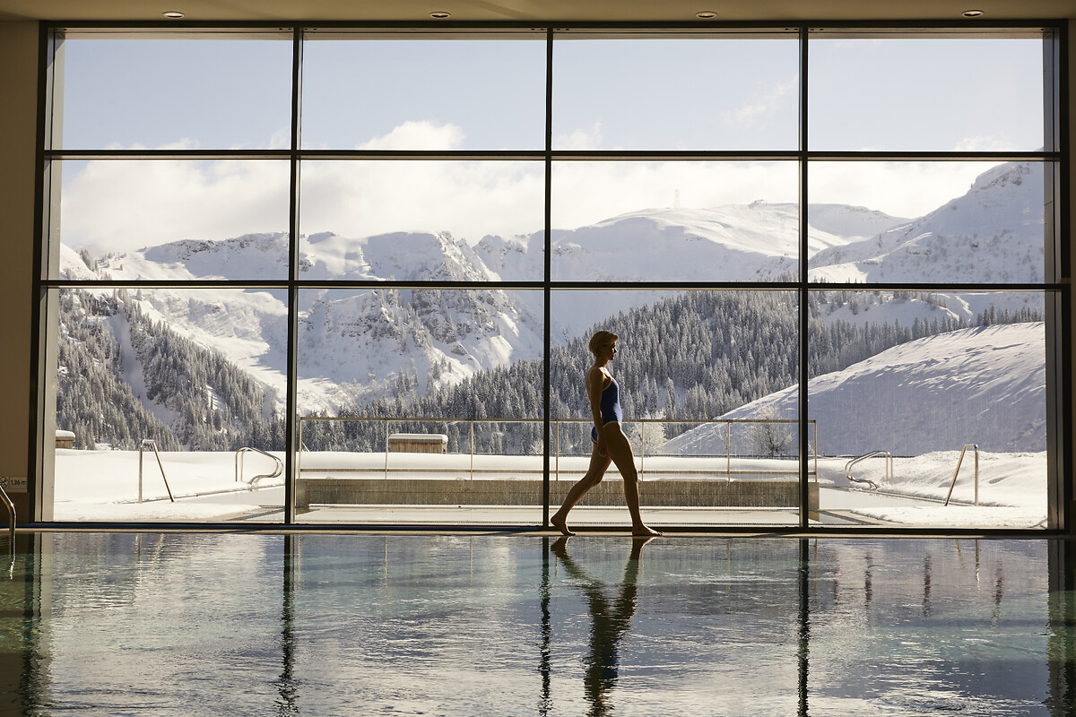 Piscina interna aquecida do spa com vista panorâmica para as montanhas nevadas